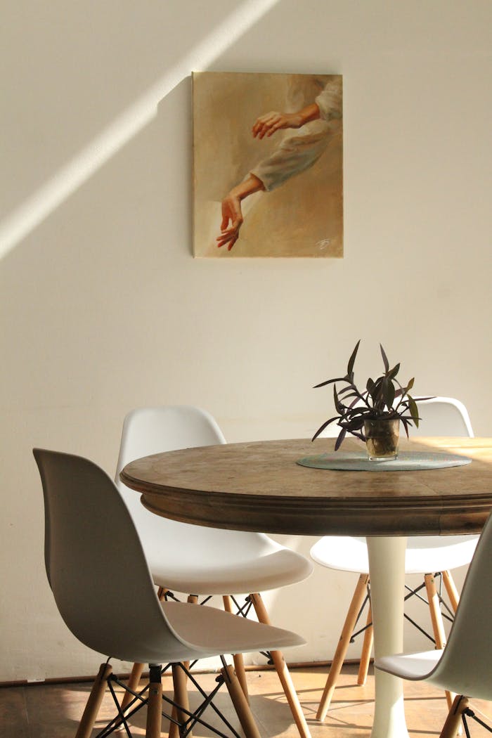 Mastering the First Impression: Your intriguing post title goes here Sunlit minimalist dining room with round table, chairs, and painting.